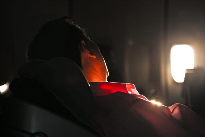 homem adormecido no banco de uma aeronave no nascer do sol