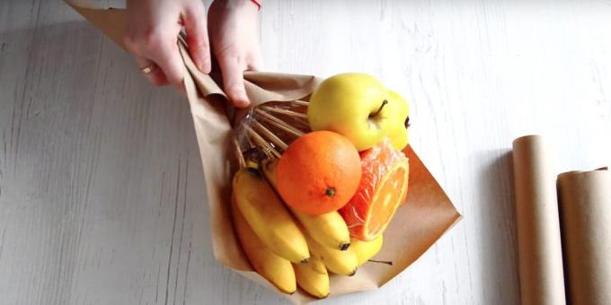 Coloque um monte de frutas com as mãos na diagonal do papel e enrole a parte inferior